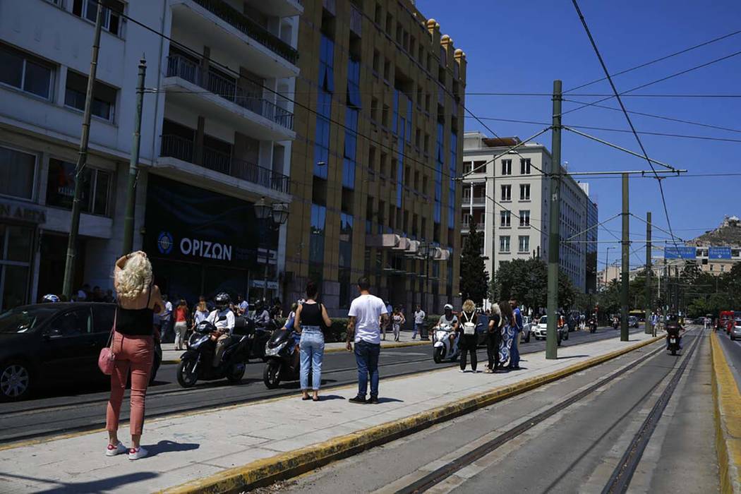 People stand outside the building they work in after a strong earthquake hit near the Greek cap ...