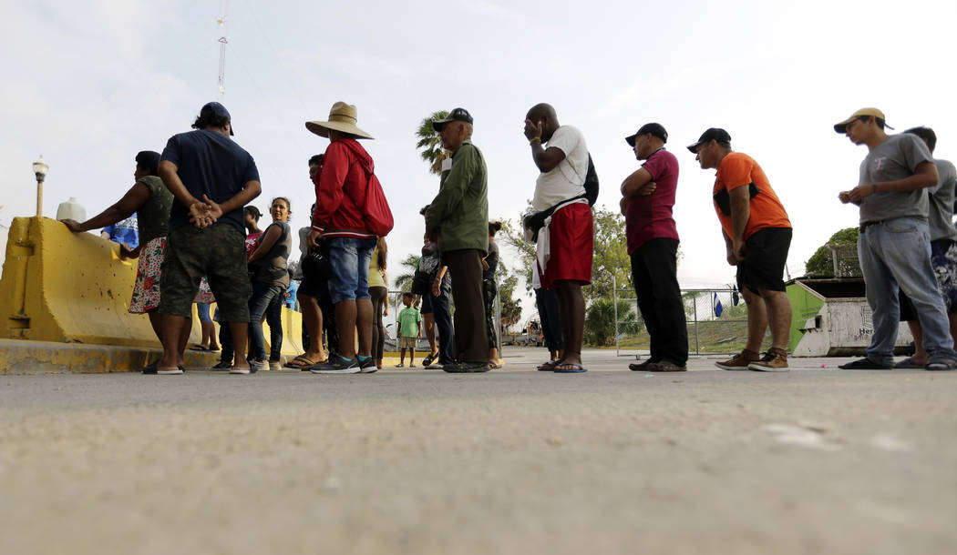 FILE - In this April 30, 2019, file photo, migrants seeking asylum in the United States line up ...