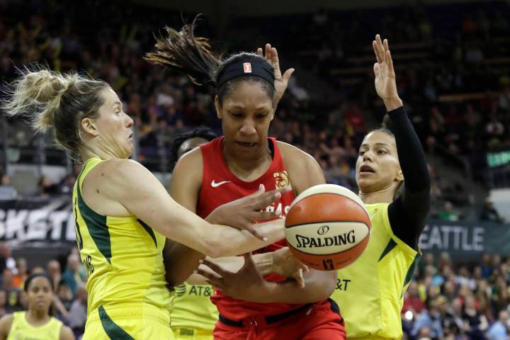 Las Vegas Aces' A'ja Wilson, center, fights for a loose ball with Seattle Storm's Sami Whitcomb ...