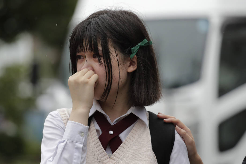 A woman sheds tears as she visits a makeshift memorial honoring the victims of Thursday's fire ...