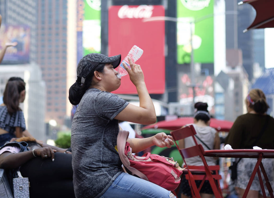 A woman drinks water in Times Square as temperatures reach the mid-to-upper 90s Saturday, July ...