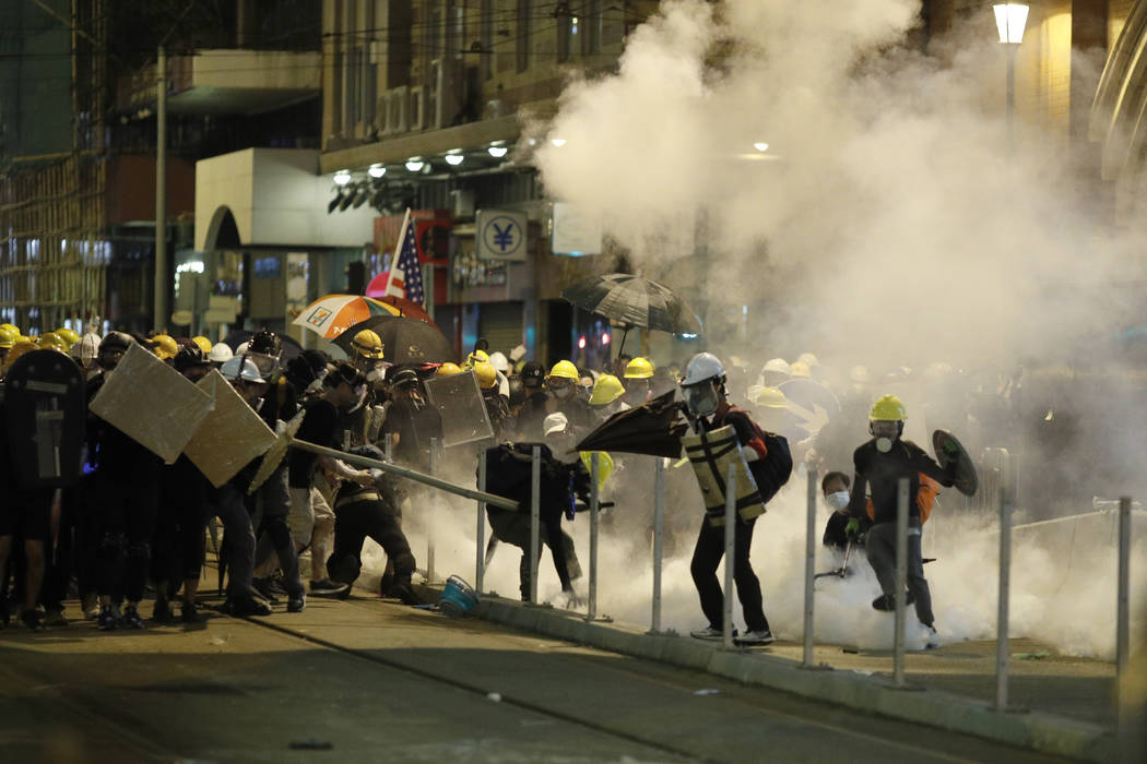 Protesters react to teargas as they confront riot police officers in Hong Kong on Sunday, July ...