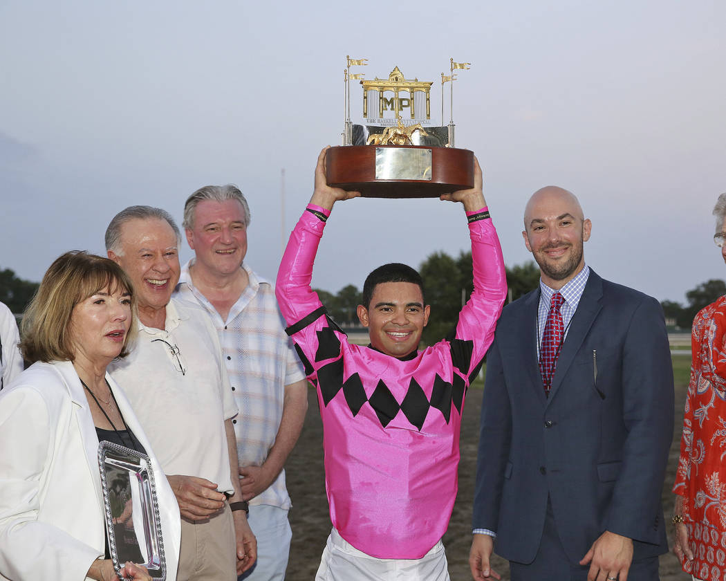 In this image provided by Ryan Denver/EQUI-PHOTO, Inc., Luis Saez, center, hoists the trophy af ...