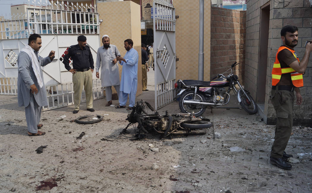 Pakistani security officials examine the site of a bombing on an entrance of a hospital in Dera ...