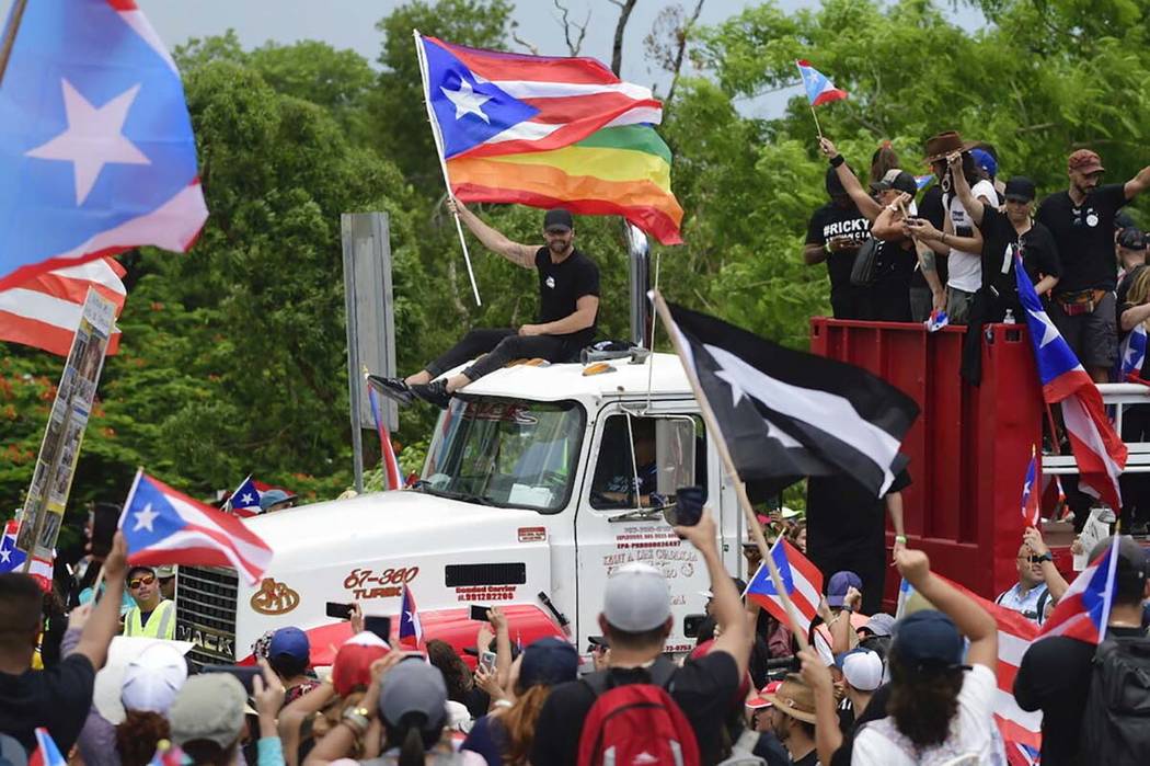 Ricky Martin, holding a Puerto Rican flag and a rainbow banner, joins thousands of Puerto Rican ...