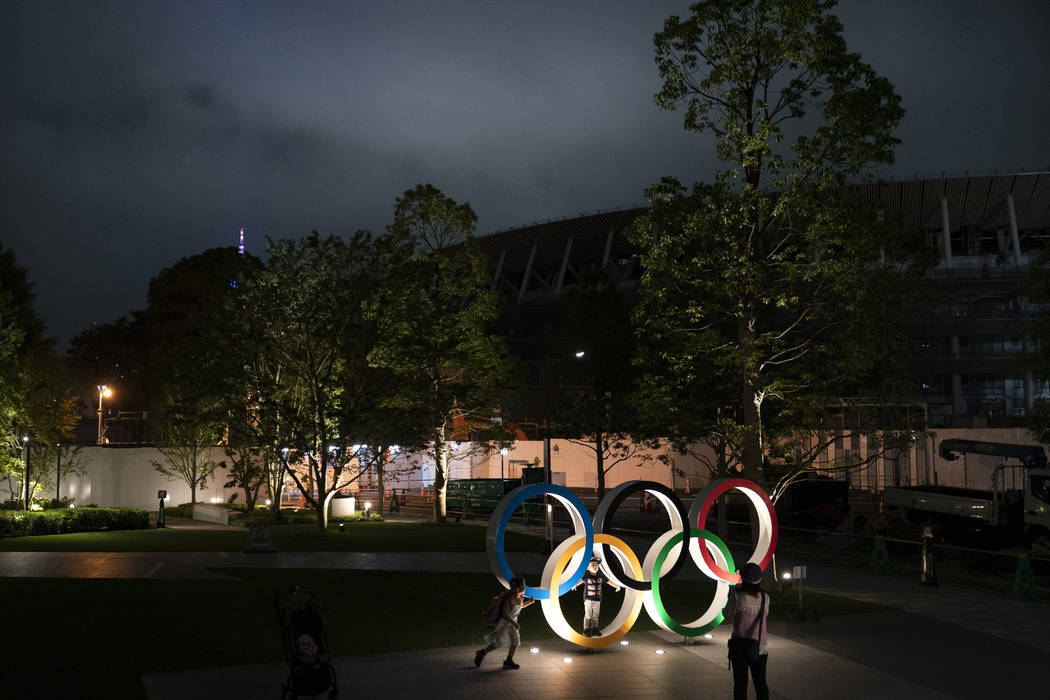 Two children pose for photos with the Olympic Rings in front of New National Stadium in Tokyo, ...