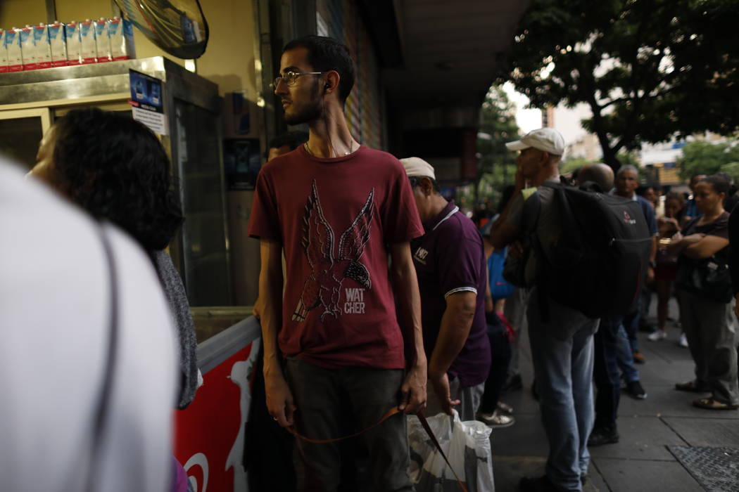 People walk in the streets of Caracas after a massive blackout left the city and other parts of ...