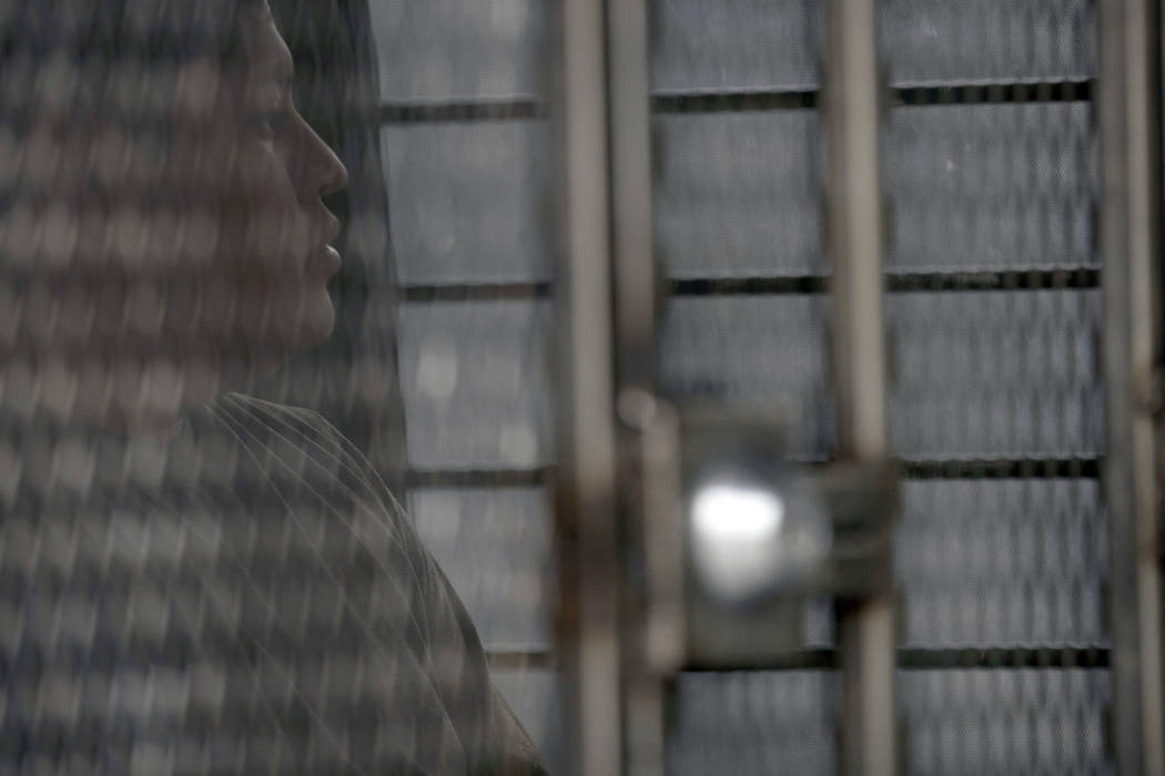 FILE - In this July 8, 2019 file photo, a man in hand and ankle cuffs waits in a van after bein ...