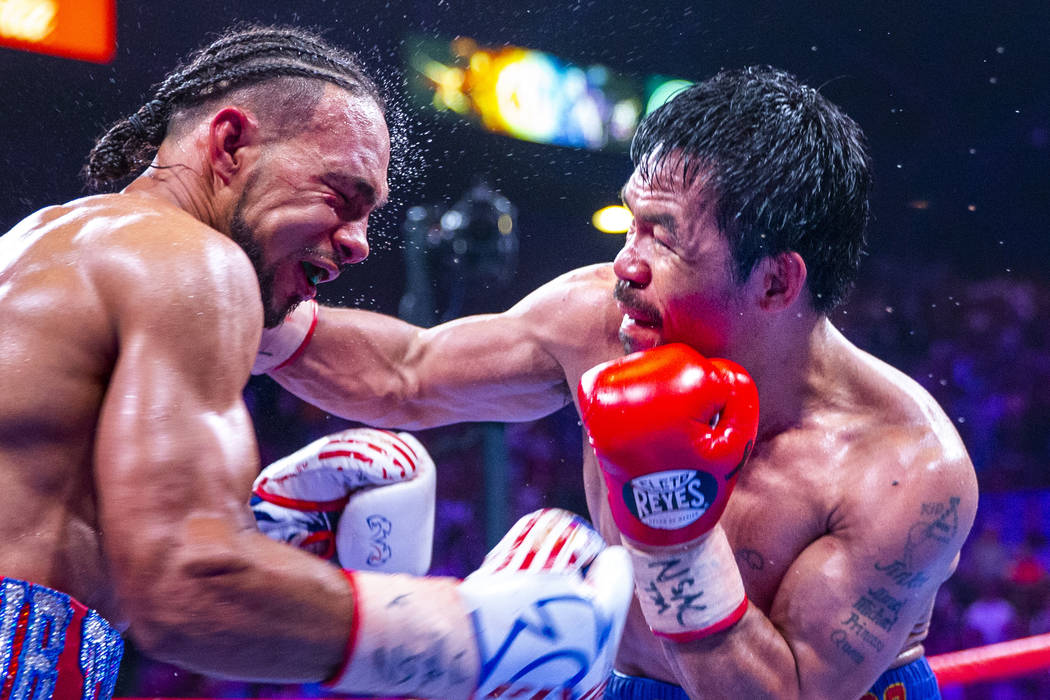 Keith Thurman, left, is punched in the face by Manny Pacquiao during Round 12 of their WBA supe ...