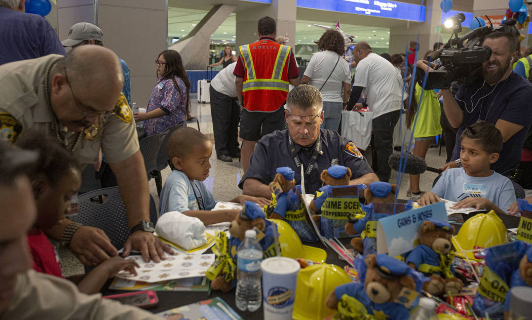 Tom Willis, 55, center, of Clark County Fire, shows Ryan Crafton, 9, left, how to make a paper ...