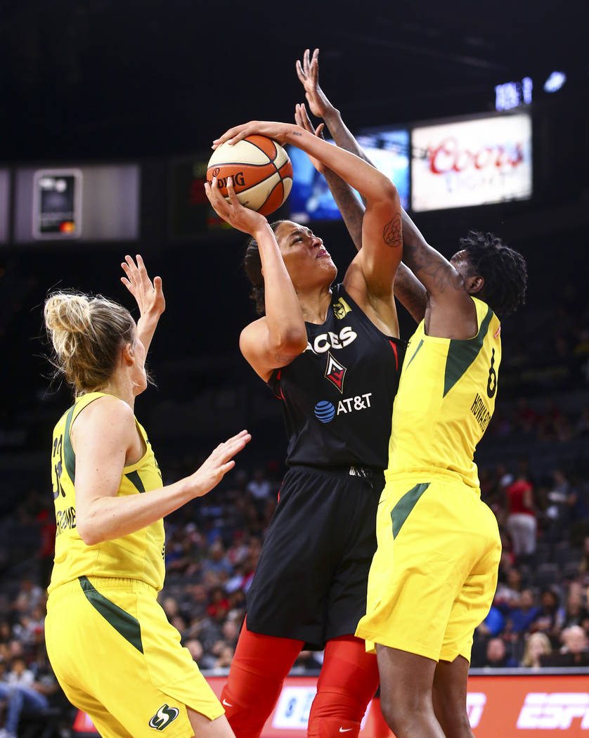 Las Vegas Aces' Liz Cambage, center, goes to the basket between Seattle Storm's Sami Whitcomb, ...