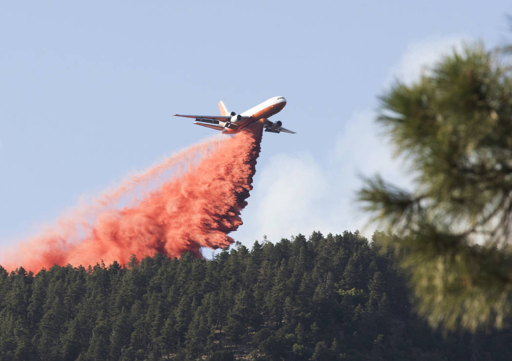 In this Sunday, July 21, 2019, photo, a tanker releases a wave of fire retardant into the crest ...