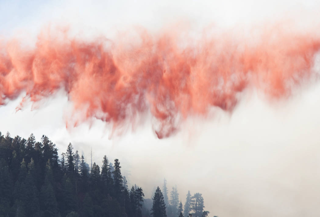 In this Sunday, July 21, 2019, photo, a wave of fire retardant prepares to touch down on the ed ...