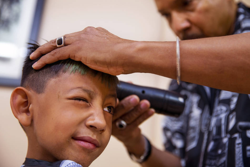 Victor Moreno, 5, squints his eye as hair stylist Thomas Rose trims him up during a back-to-sch ...