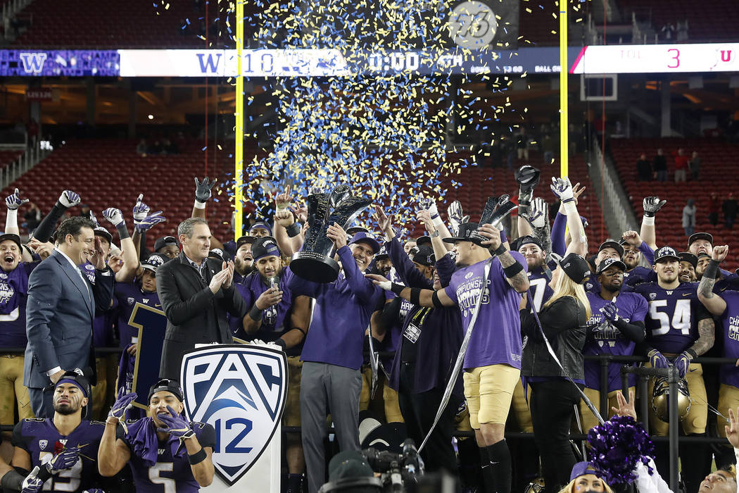 Washington coach Chris Petersen, center, raises the trophy as he celebrates with his players af ...