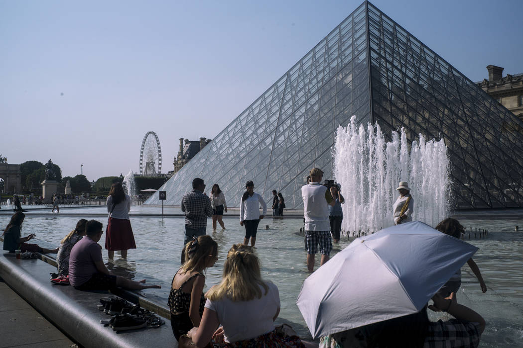 People cool off next to the fountains at Louvre Museum in Paris, France, Wednesday, July 24, 20 ...