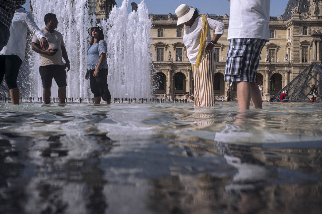 People cool off next to the fountains at Louvre Museum in Paris, France, Wednesday, July 24, 20 ...