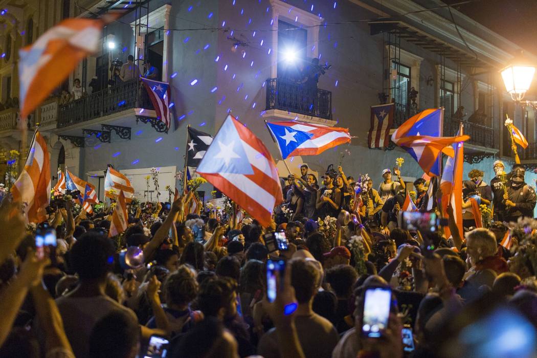 People celebrate outside the governor's mansion La Fortaleza, after Gov. Ricardo Rossello annou ...