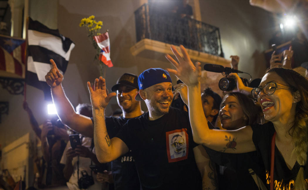 Singer Rene Perez Joglar celebrates outside the governor's mansion La Fortaleza, after Gov. Ric ...