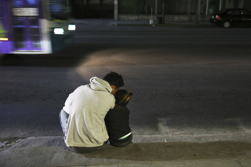 In this July 18, 2019 photo, a migrant father and daughter sit on the sidewalk after getting of ...