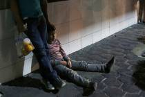 In this July 18, 2019 photo, a migrant child and his father stay together after being bused by ...