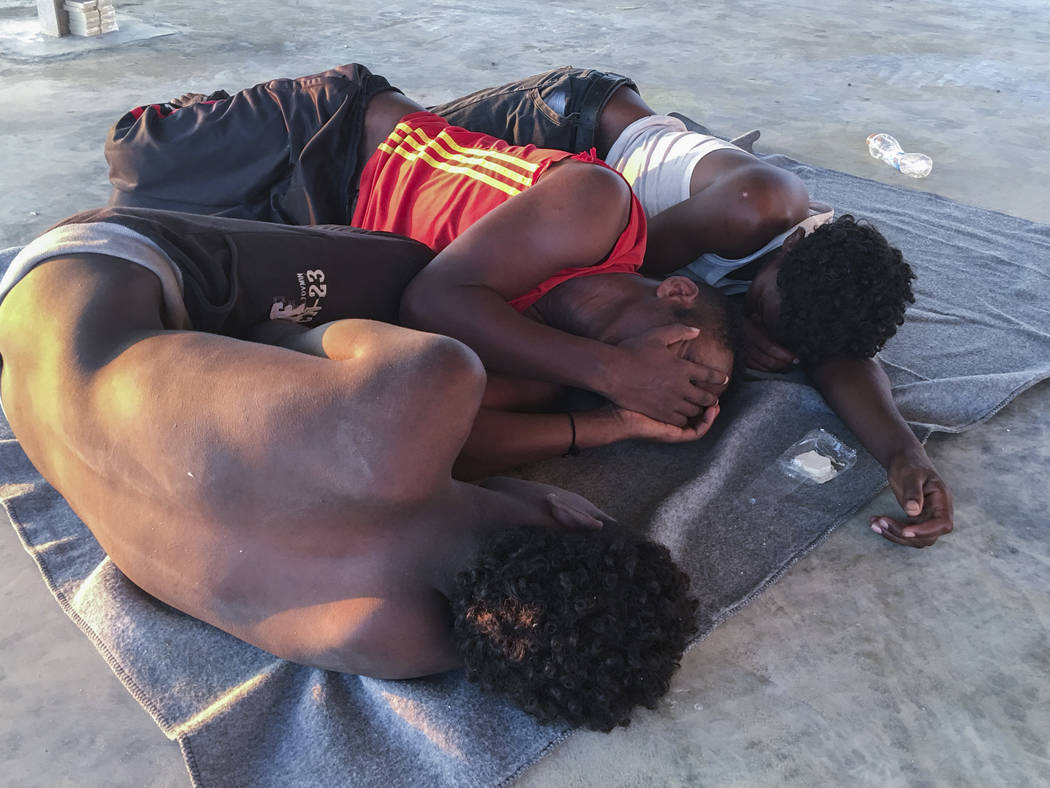 Rescued migrants rest on a coast some 100 kilometers (60 miles) east of Tripoli, Libya, Thursda ...