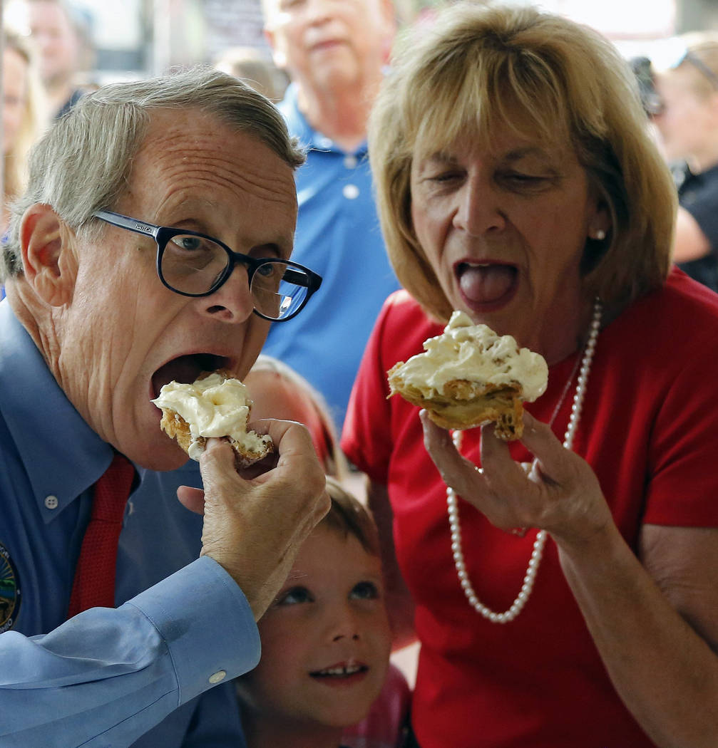 Ohio Gov. Mike DeWine and Fran DeWine eat a cream puff at Schmidt's while grandchild Steven Dud ...