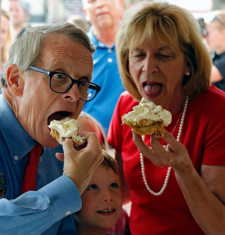 Ohio Gov. Mike DeWine and Fran DeWine eat a cream puff at Schmidt's while grandchild Steven Dud ...