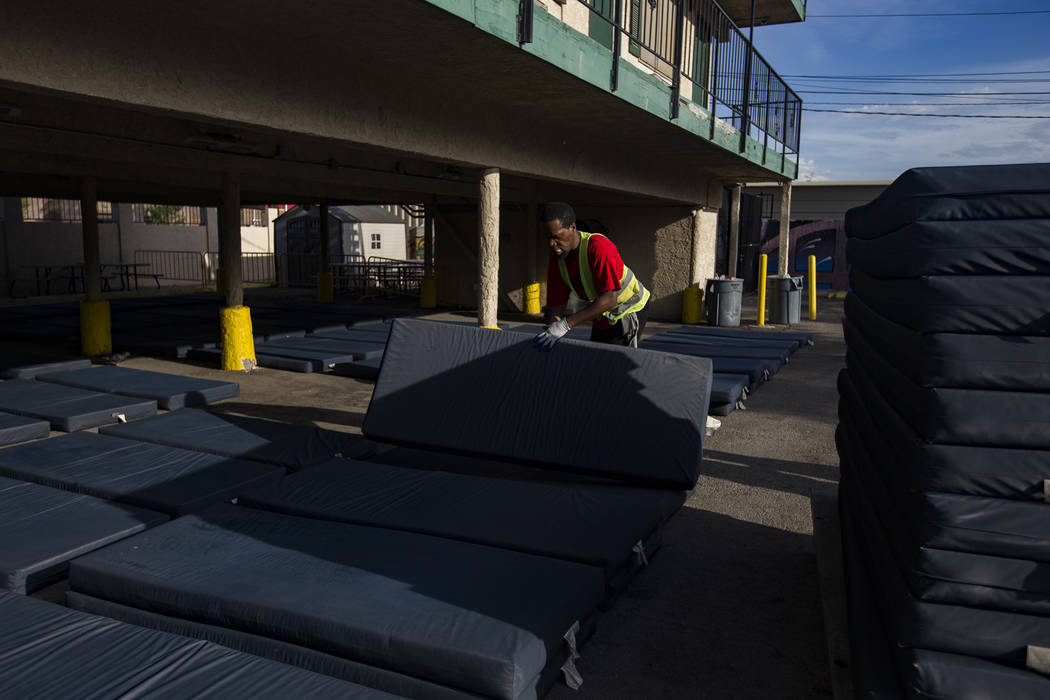 Chukwunedu Arah, a volunteer, places bed mats for clients at the Courtyard Homeless Resource Ce ...
