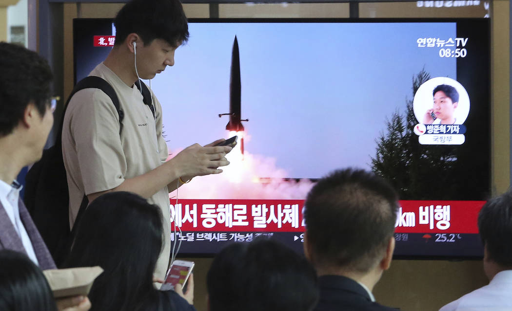 People watch a TV showing a file image of North Korea's missile launch during a news program at ...