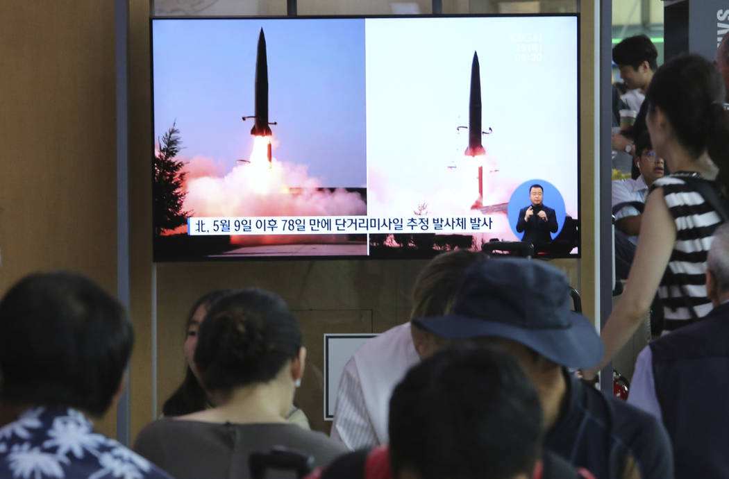 People watch a TV showing file images of North Korea's missile launch during a news program at ...