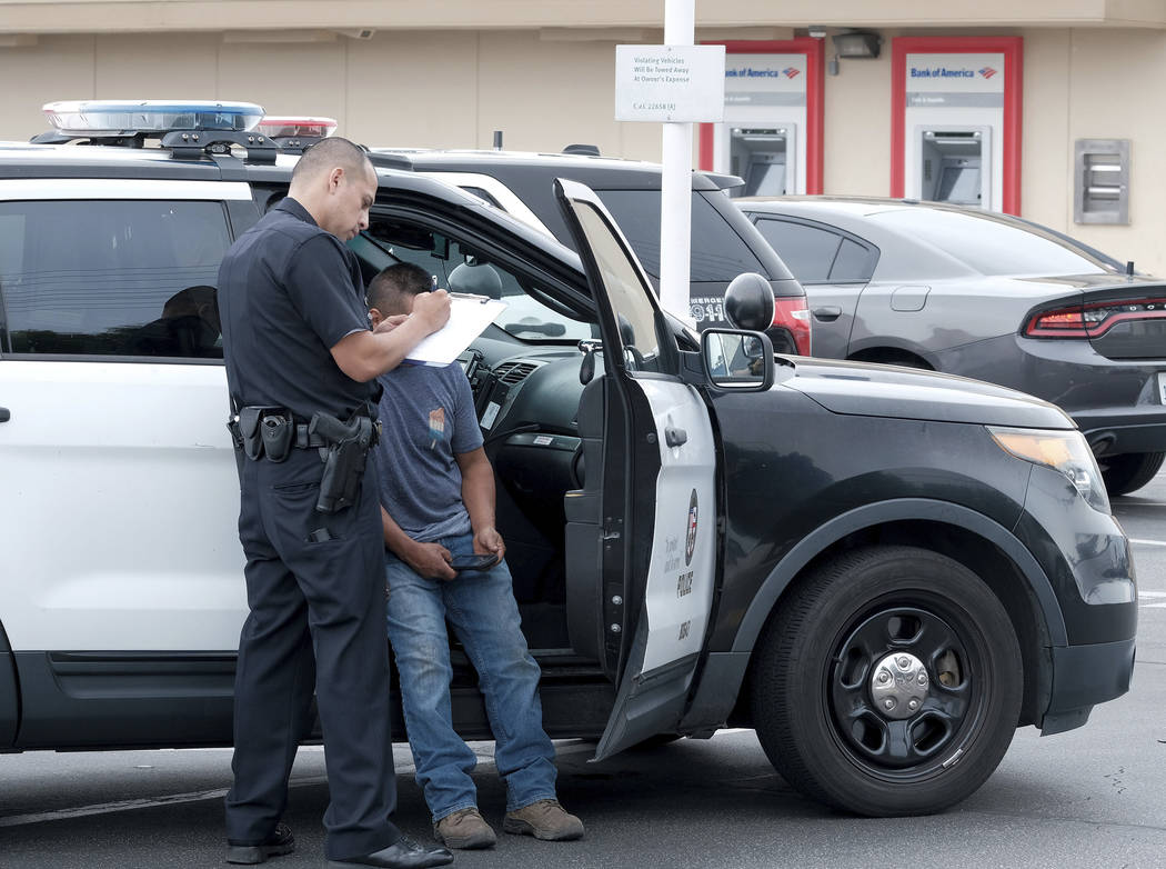 A LAPD officer talks to the victim of an attempted robbery in Los Angeles on Thursday, July 25, ...