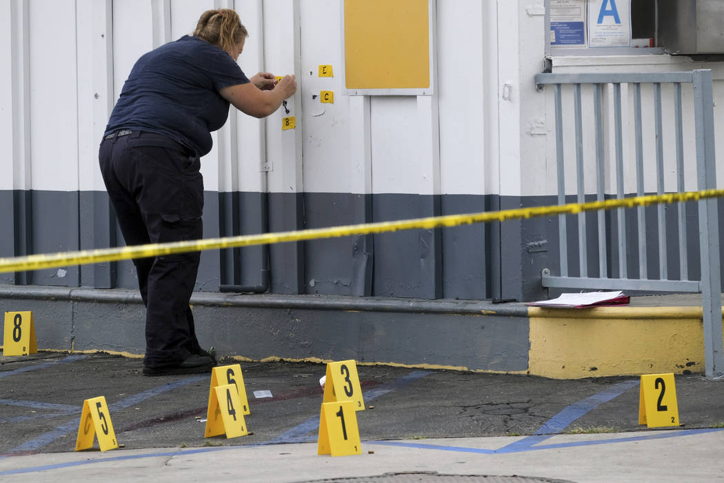 LAPD crime investigators collect evidence at one of the scenes of a shooting, a Shell gas stati ...