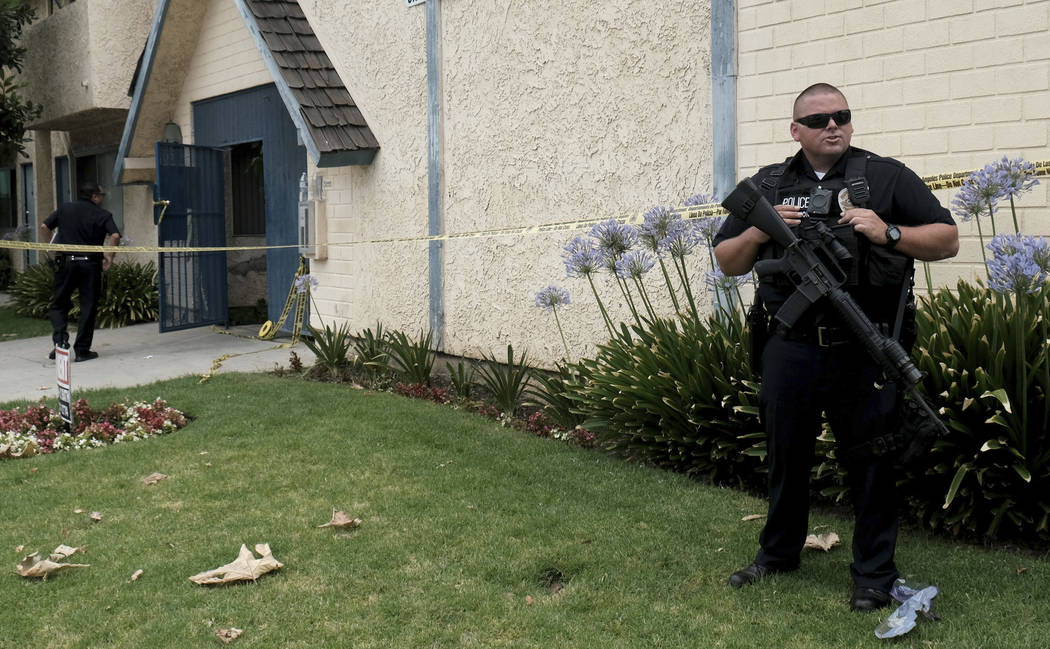 A Los Angeles police officer stands outside of an apartment where a shooting occurred in the Ca ...