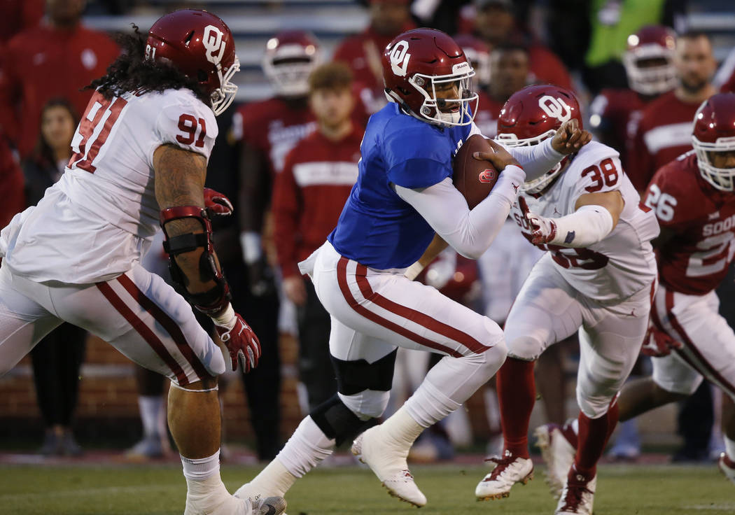 Oklahoma quarterback Jalen Hurts (1) carries between defenders Dillon Faamatau (91) and Bryan M ...