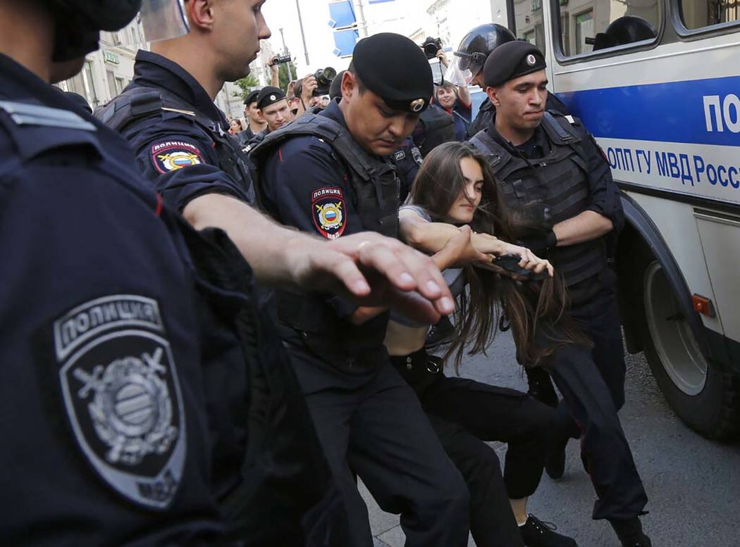 Police officers detain a woman prior to an unsanctioned rally in the center of Moscow, Russia, ...