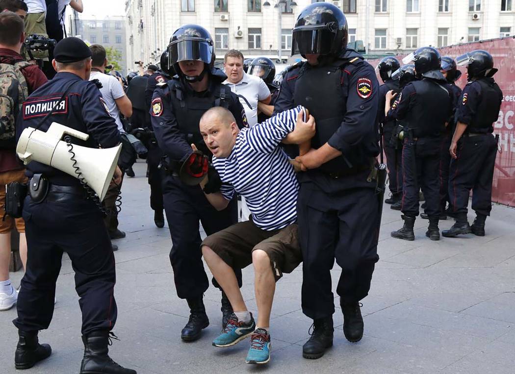 Police officers detain a man during an unsanctioned rally in the center of Moscow, Russia, Satu ...