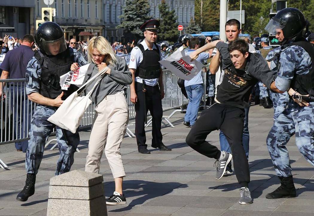 Police officers detain people during an unsanctioned rally in the center of Moscow, Russia, Sat ...