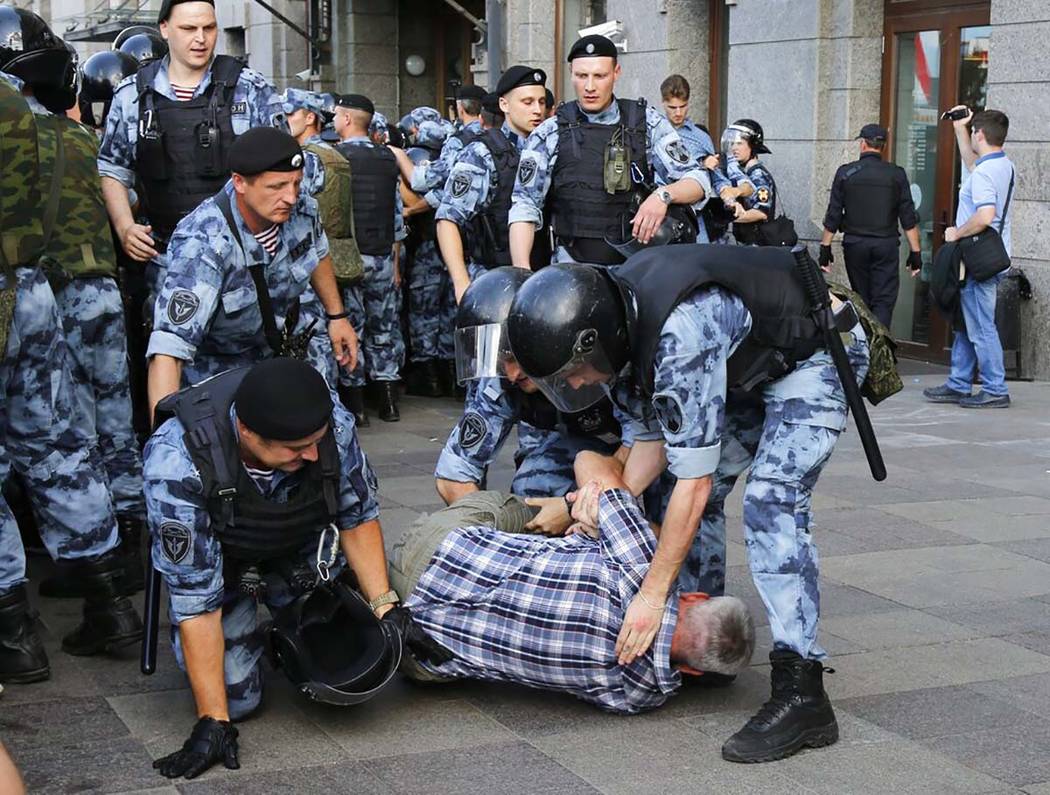 Police officers detain a man during an unsanctioned rally in the center of Moscow, Russia, Satu ...