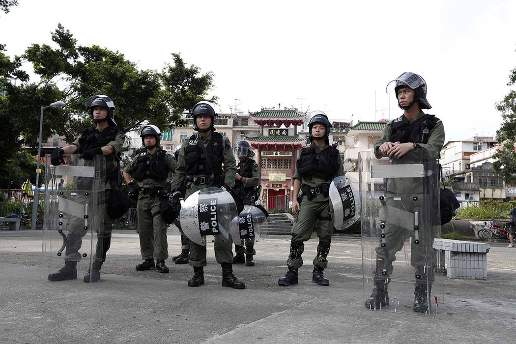 Riot police guard the entrance to a village at Yuen Long district in Hong Kong Saturday, July 2 ...