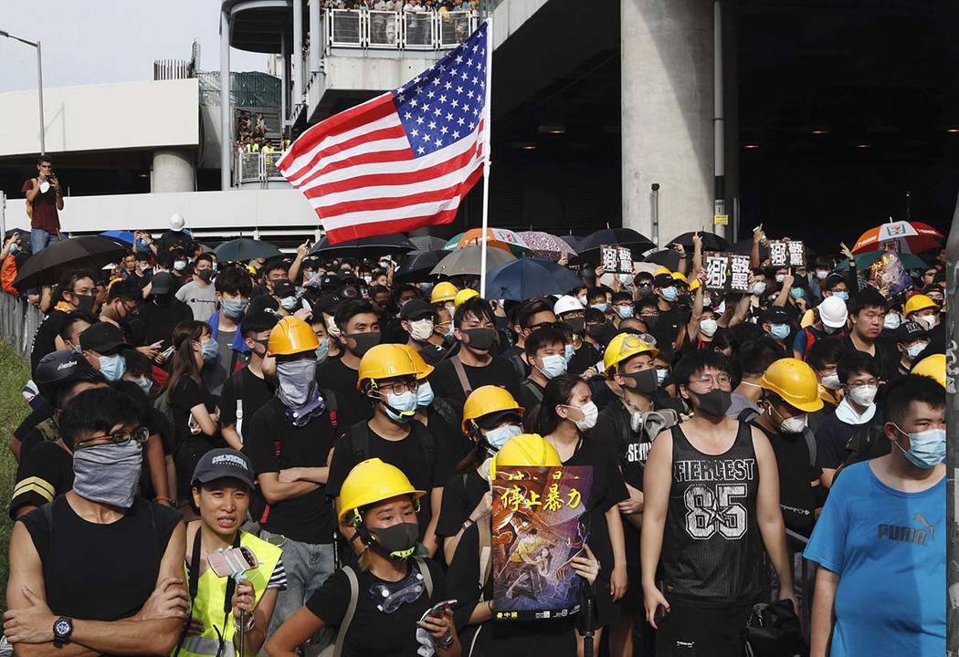 Protesters hold up a poster with the words "Stop violence" and a U.S. flag as they fa ...