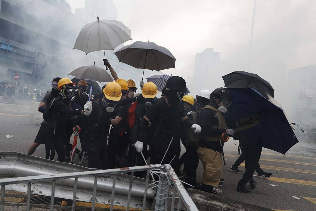 Protesters react to tear gas during a face off with riot police at Yuen Long district in Hong K ...