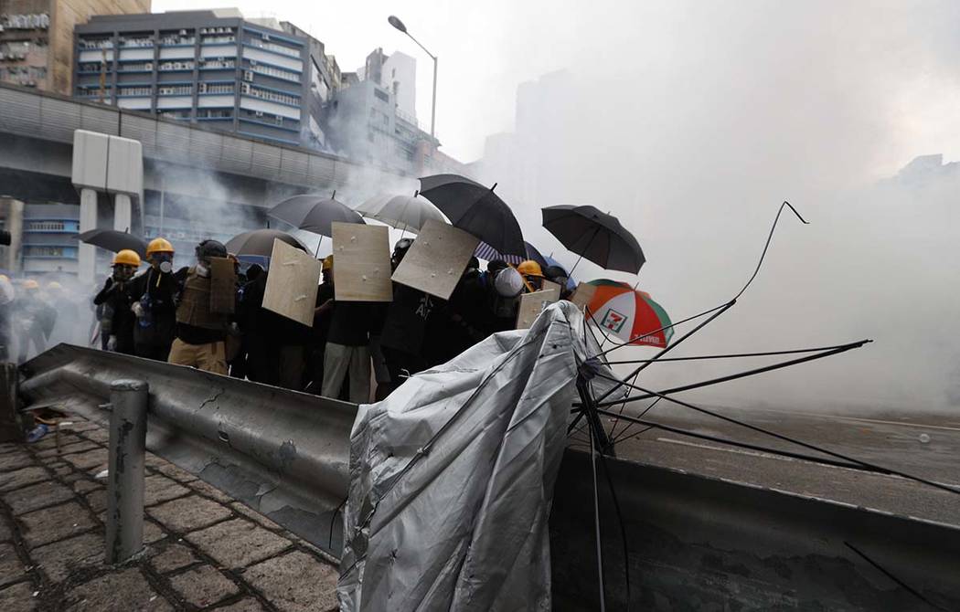 Protesters react to tear gas during a face off with riot police at Yuen Long district in Hong K ...