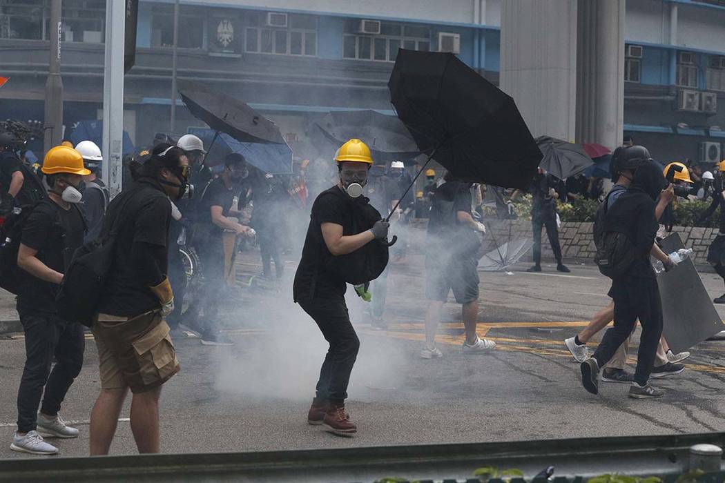 Protesters react to tear gas during a face off with riot police at Yuen Long district in Hong K ...