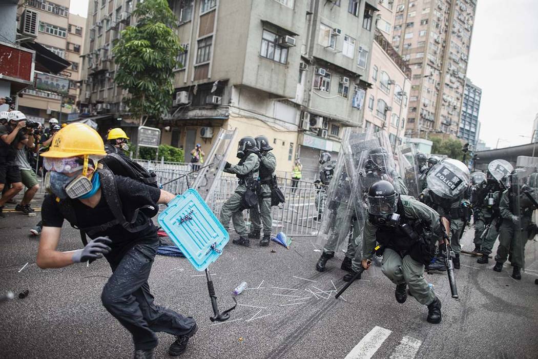 A protester flee from baton wielding police in Yuen Long district in Hong Kong on Saturday, Jul ...