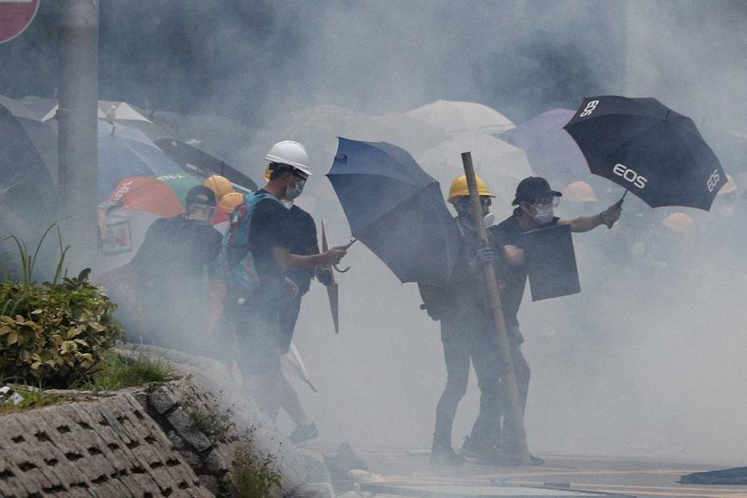 Protesters react to tear gas during a face off with riot police in Yuen Long district in Hong K ...