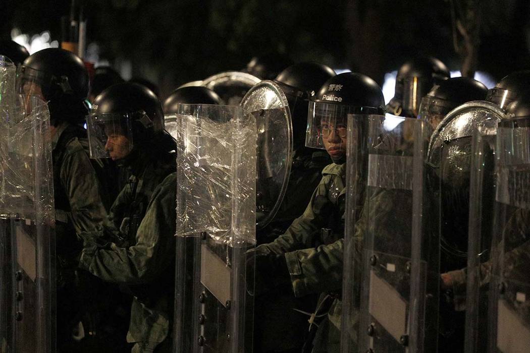 Riot police stand behind shields as they face off protesters in Yuen Long district in Hong Kong ...