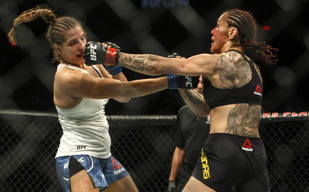 Cris Cyborg, right, hits Felicia Spencer during a mixed martial arts bout at UFC 240, in Edmont ...