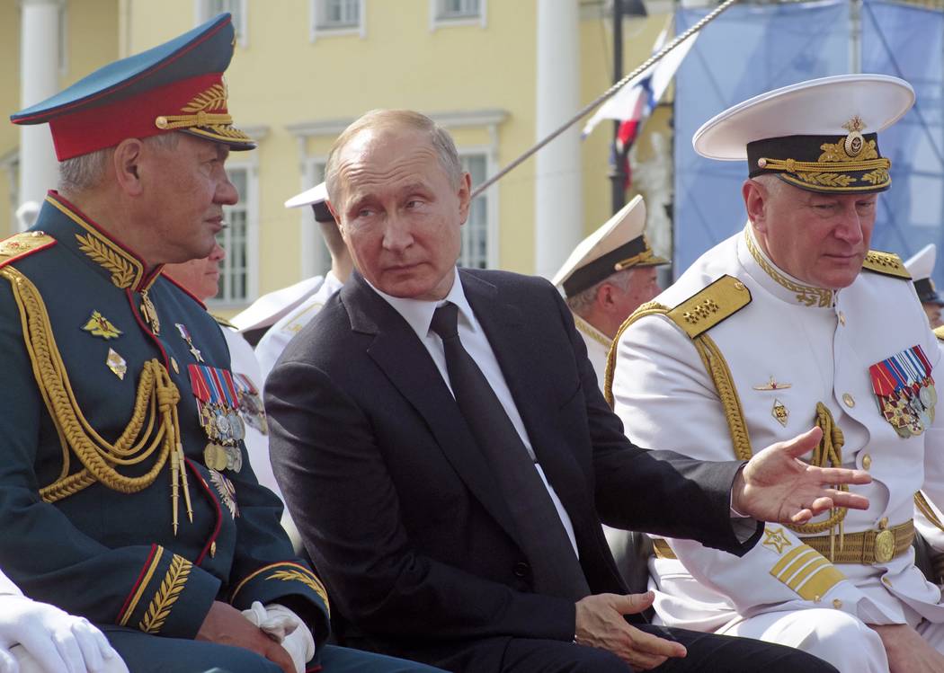 Russian President Vladimir Putin, centre, gestures while speaking to Defence Minister Sergei Sh ...