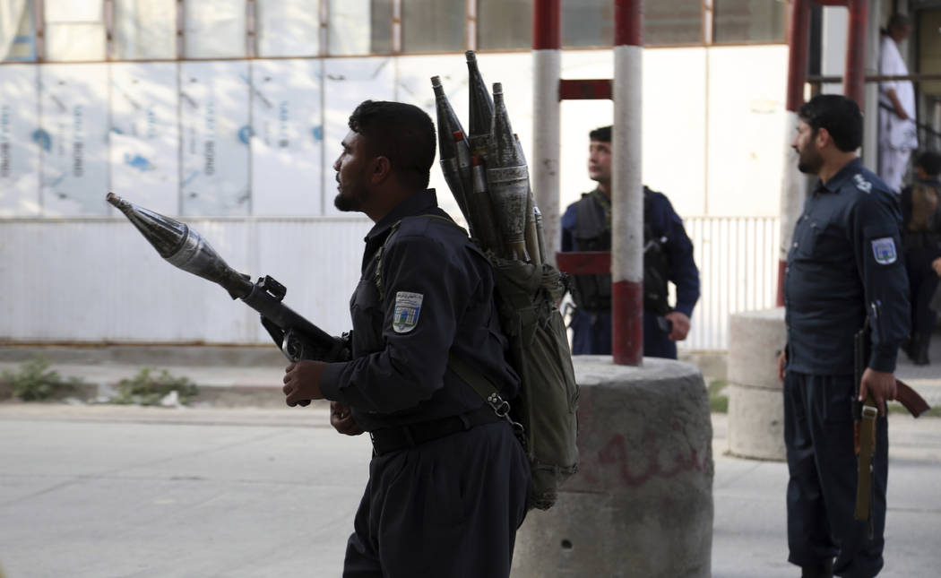 Afghan security personnel stand guard at the site of a deadly attack in Kabul, Afghanistan, Sun ...